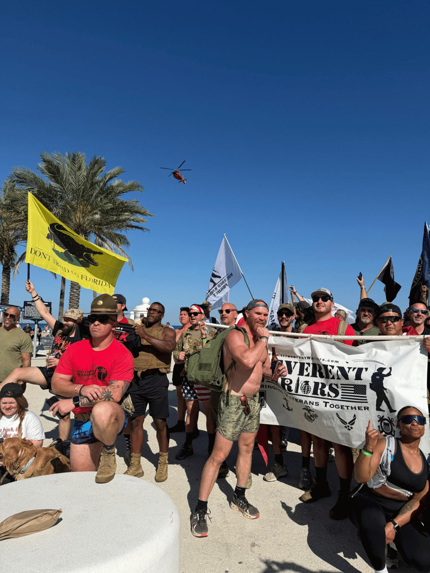Rally Point veterans at the beach with flags and Coast Guard helicopter